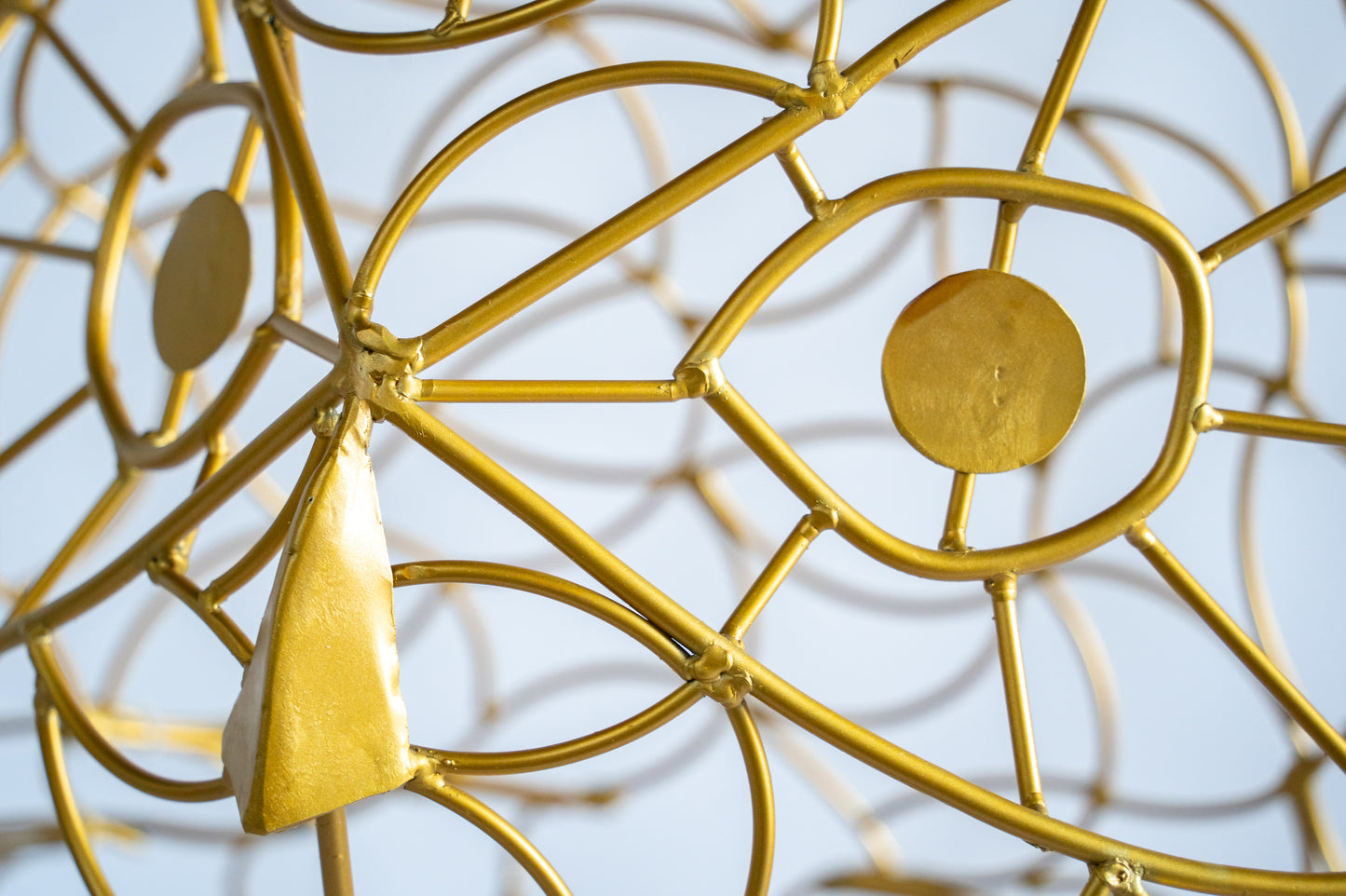 Close-up of the golden eye and nose structure of the Alganic light owl, handcrafted wire sculpture
