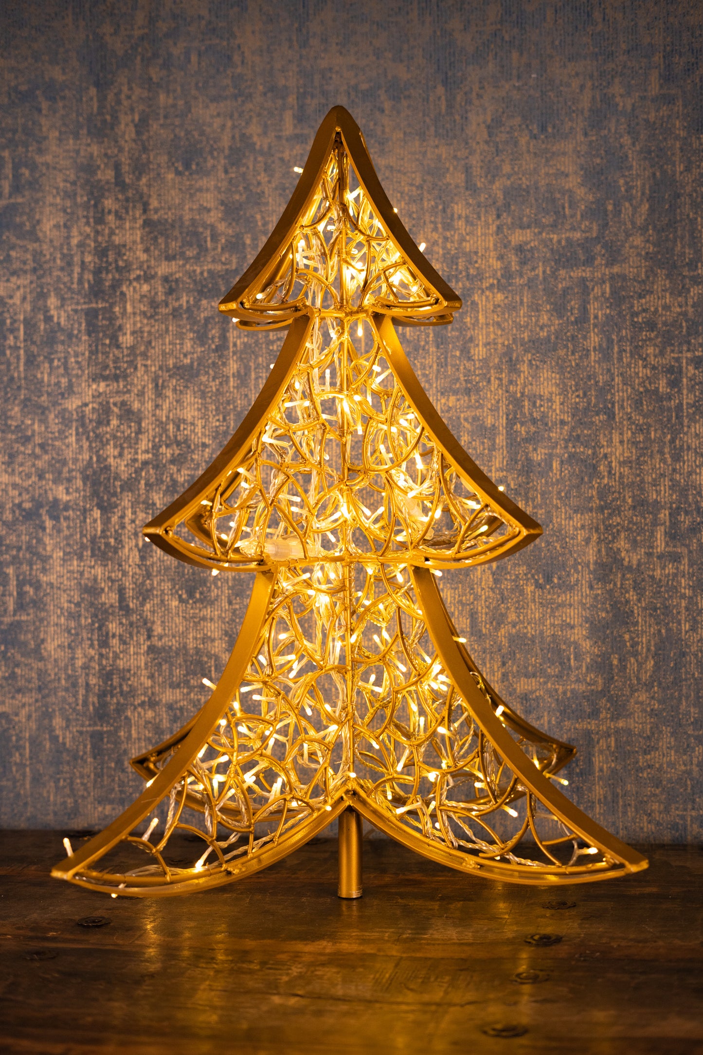 LED-Weihnachtsbaum aus goldfarbenem Aluminium, 90 cm – inszeniert vor Holzoptik für stilvolle Innenraumgestaltung