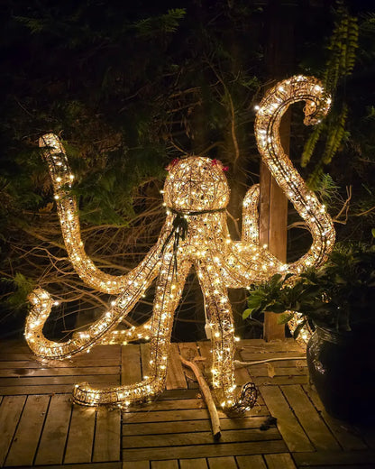 Beleuchtete Oktopus-Skulptur aus Draht im nächtlichen Garten – goldenes Lichtobjekt mit bewegter Tentakelstruktur und poetischer Präsenz.